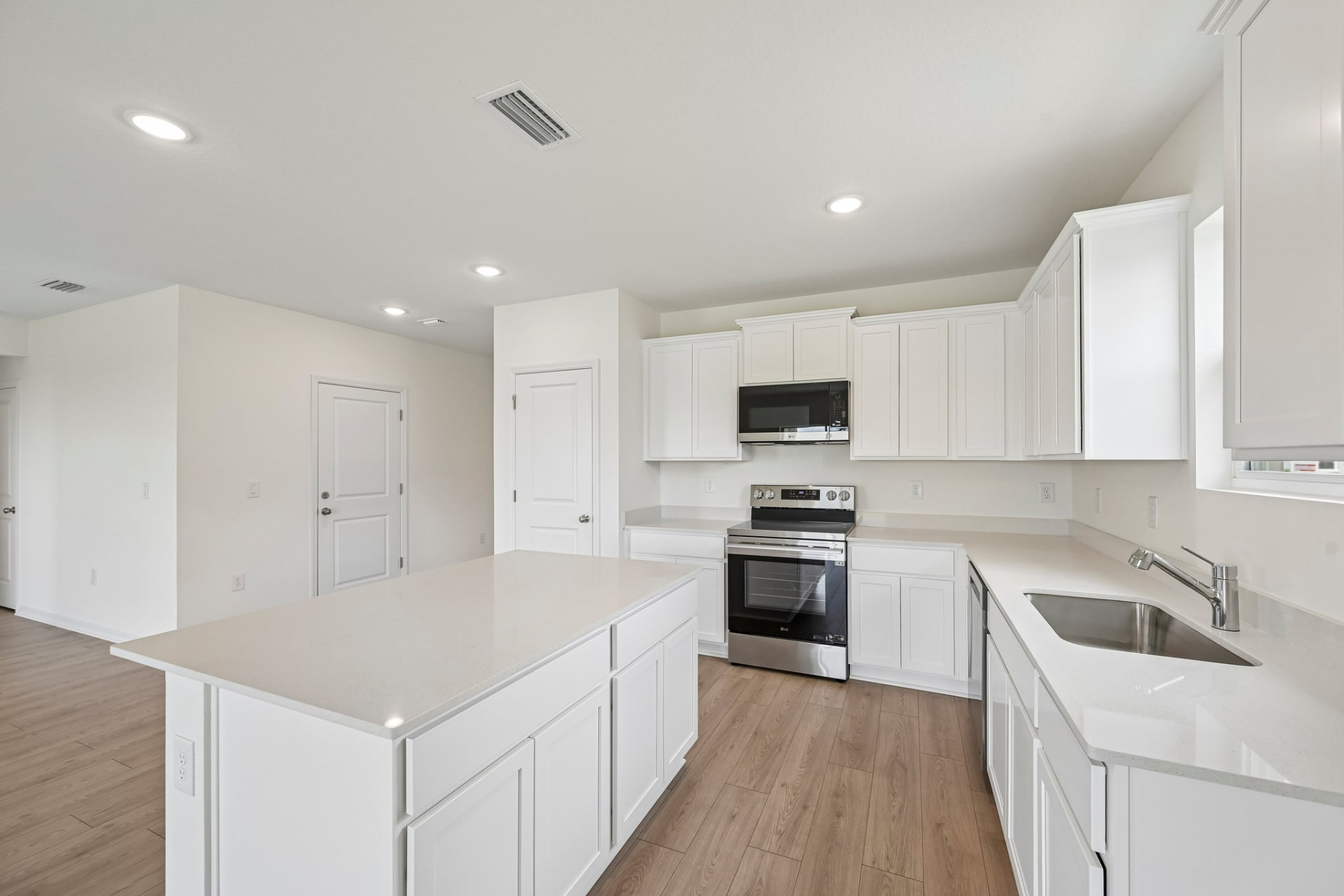White shaker kitchen with quartz island and stainless steel appliances