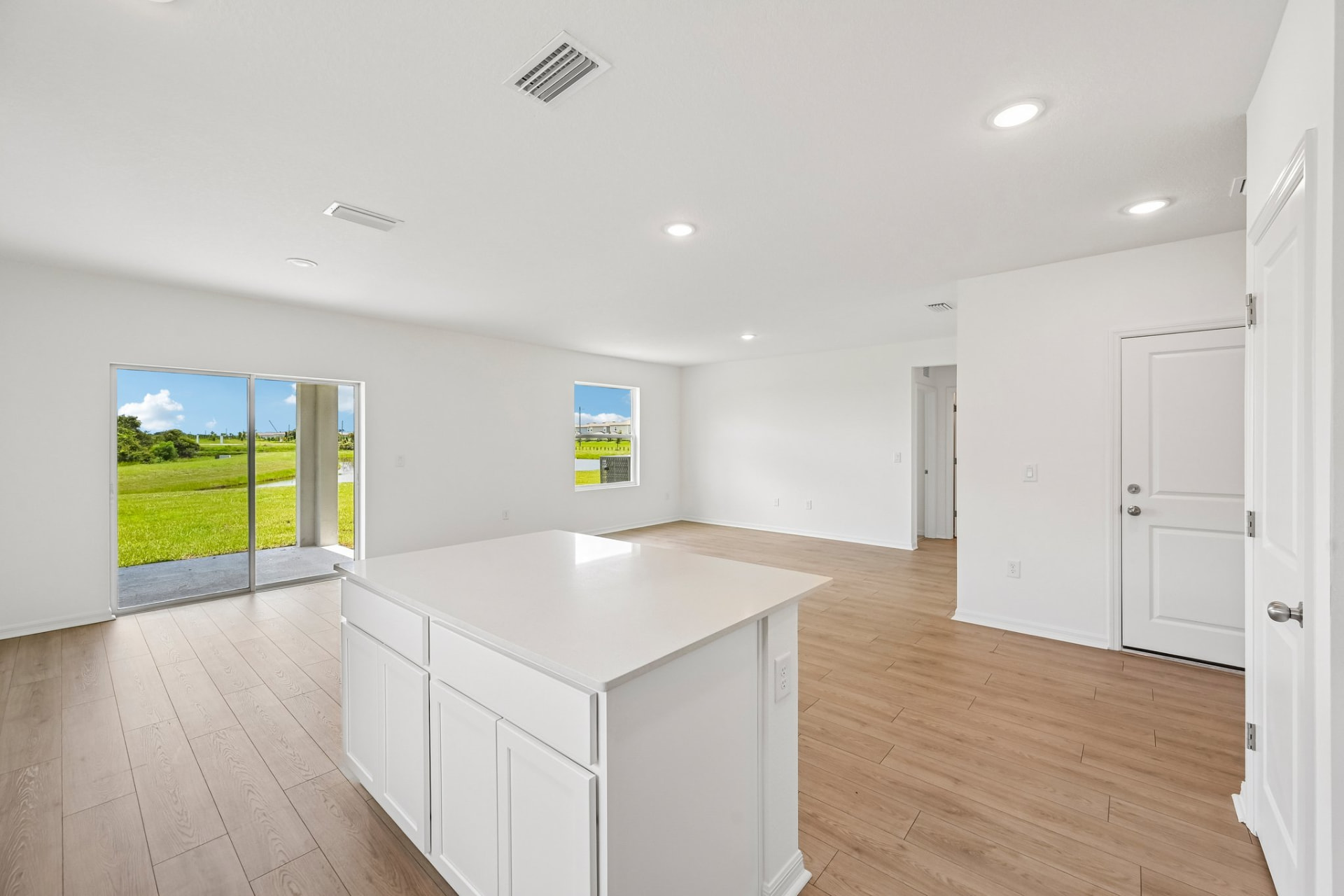 Open living area with wood-look flooring and sliding doors to a pond view